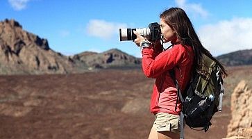 Una ragazza fotografa con un teleobiettivo durante un giro in montagna.