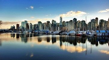 Skyline di Vancouver, specchiato nell'acqua, al tramonto.