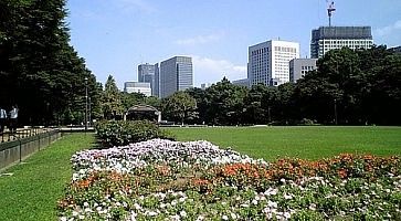 Il parco Hibiya Park in primavera, con molti fiori e alcuni edifici in lontananza.