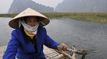 Donna con cappello tradizionale vietnamita, su un'imbarcazione.