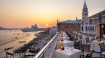 Tavoli pronti per la cena all'hotel Danieli Venezia, e in lontananza il sole al tramonto.