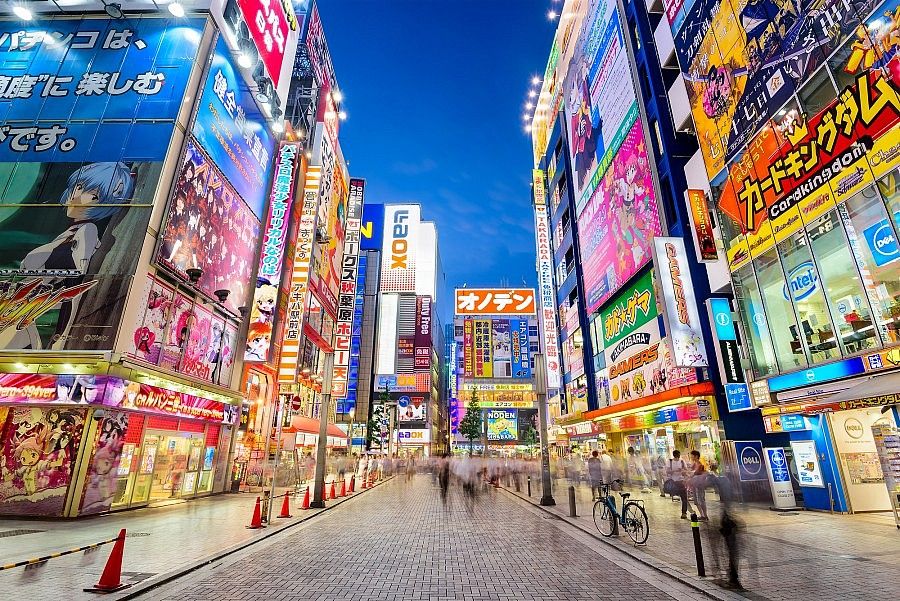 Strada di Akihabara a Tokyo con luci al neon e negozi colorati.