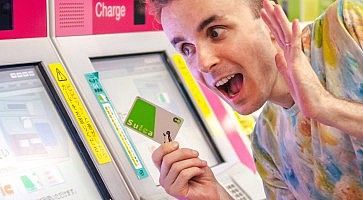 Marco Togni in stazione a Tokyo, con in mano una carta ricaricabile Suica, vicino alle biglietterie automatiche.