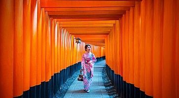 Una donna in kimono cammina tra i portali rossi del Fushimi Inari a Kyoto.