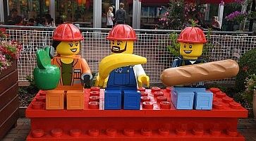 Tre omini lego, vestiti da operai in pausa pranzo.