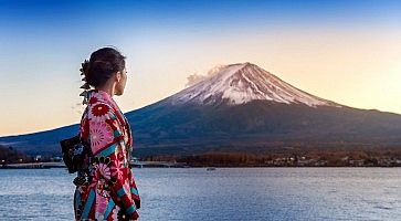 Ragazza asiatica indossa un kimono; sullo sfondo il lago Kawaguchi-ko e il Monte Fuji al tramonto.