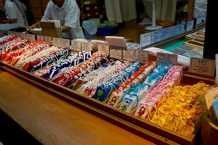 Amuleti giapponesi colorati disposti su un banco espositivo.