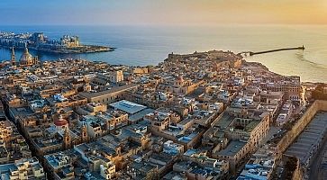 Valletta, Malta - Aerial panoramic view of Valletta with Mount Carmel church, St.Paul's and St.John's Cathedral, Manoel Island, Fort Manoel, Sliema and cruise ship entering Grand Harbor at sunrise