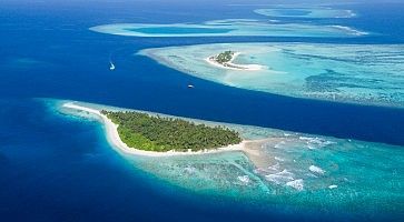 Small tropical island in Maldives atoll from aerial view