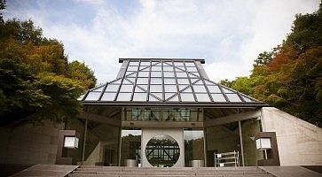 Ingresso del Museo Miho con struttura in vetro e natura circostante.