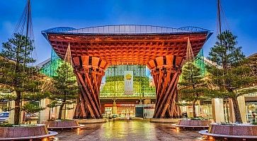 Il grande e moderno torii che segna l'ingresso della stazione di Kanazawa, di sera.