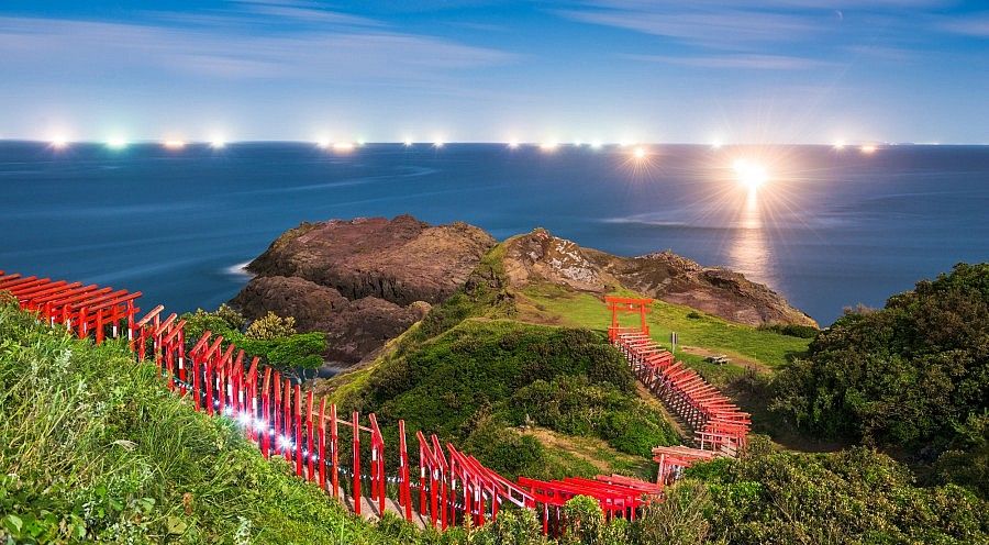 File di "giorni-festivi-giappone.jpg": file di torii rossi verso il mare al tramonto.
