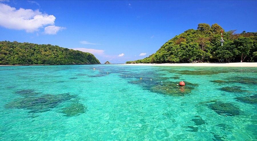 Spiaggia tropicale con mare turchese e isole verdi in Thailandia.