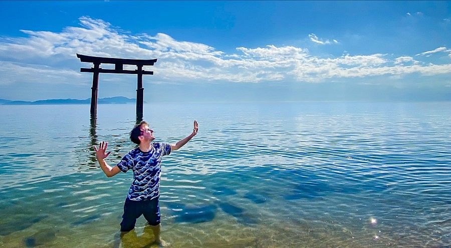 Un torii nel lago davanti al Santuario Shirahige con una Marco Togni nell\'acqua.