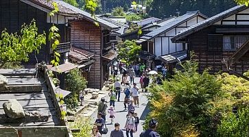 Strada fiancheggiata da case tradizionali in Giappone con persone che passeggiano.