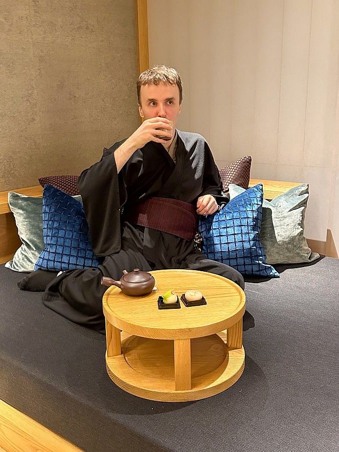 Una persona in kimono che beve tè seduta in un ambiente elegante a Hoshinoya Tokyo.