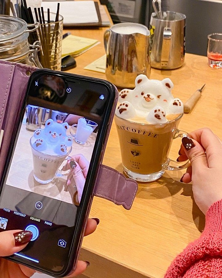 Cappuccino decorato con schiuma a forma di orsetto su tavolo di Hatcoffee.