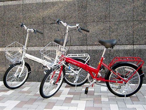 Due biciclette pieghevoli, una rossa e una bianca, appoggiate a un muro.