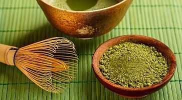 Polvere di matcha, una tazza e l'utensile per mischiare e preparare il tè matcha.