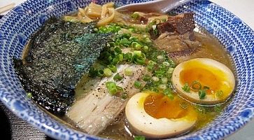 Ramen con brodo denso, pezzi di carne e uovo.