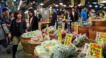 Persone camminano tra le bancarelle di cibi particolari, al Nishiki Market a KYoto.