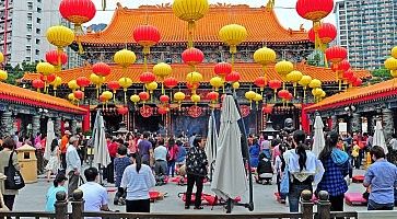 Il tempio di Wong Tai Sin, con lanterne gialle e rosse, e molte persone durante una celebrazione.