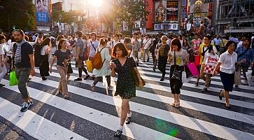 Persone attraversano il grande incrocio di Shibuya.