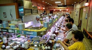 Clienti intengi a mangiare al ristorante di Musashi Sushi, a Kyoto, specializzato in kaiten sushi.